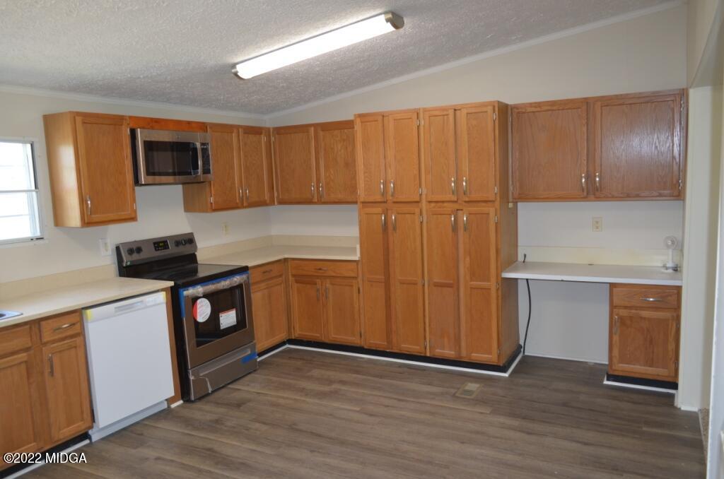 171 Dillon Road Butler, GA 31006 - Photo 9 of 22 a kitchen with granite countertop wooden cabinets and a stove top oven