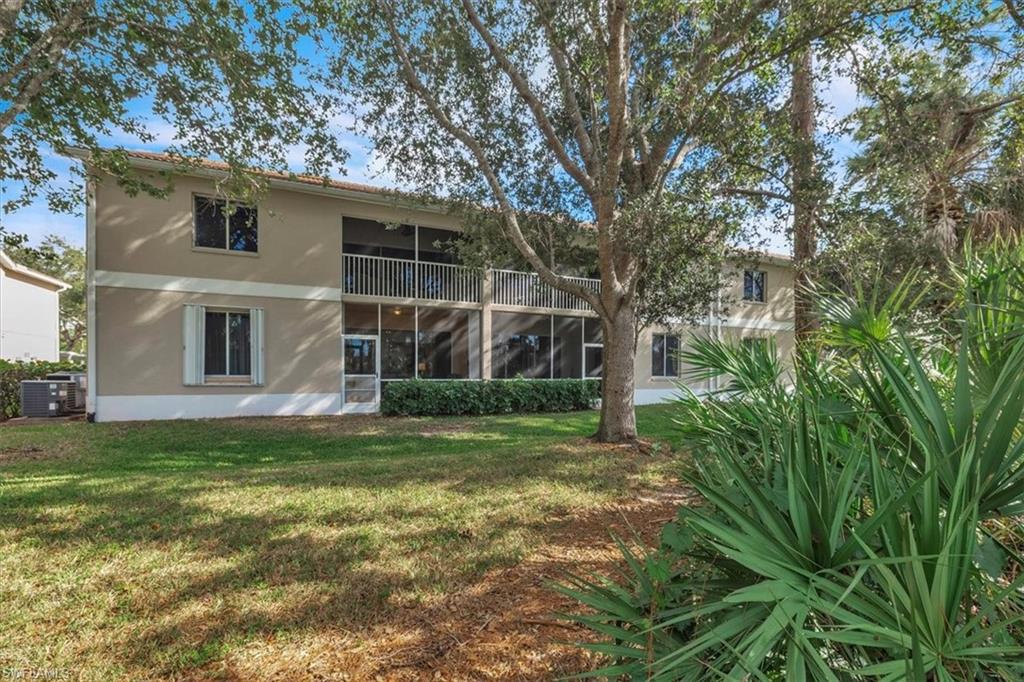 8075 Tiger Cove, Unit 1706 Naples, FL 34113 - Photo 36 of 50 Back of property with a sunroom, stucco siding, a balcony, and a lawn