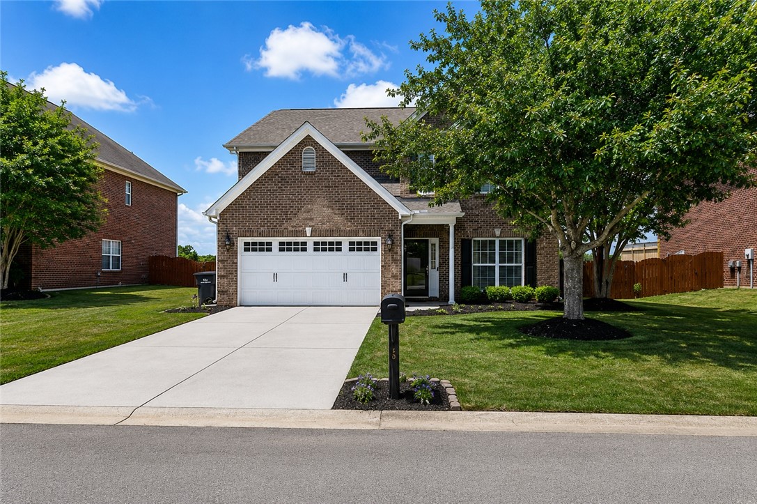This classic brick residence features a pristine lawn and a welcoming driveway.