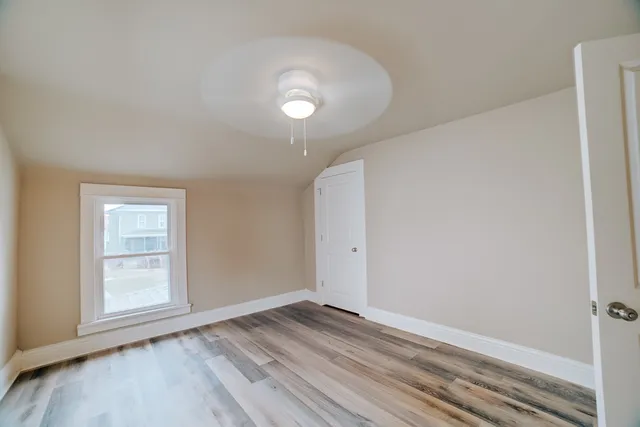 an empty room with wooden floor and windows