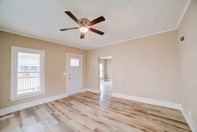 a view of empty room with wooden floor and fan