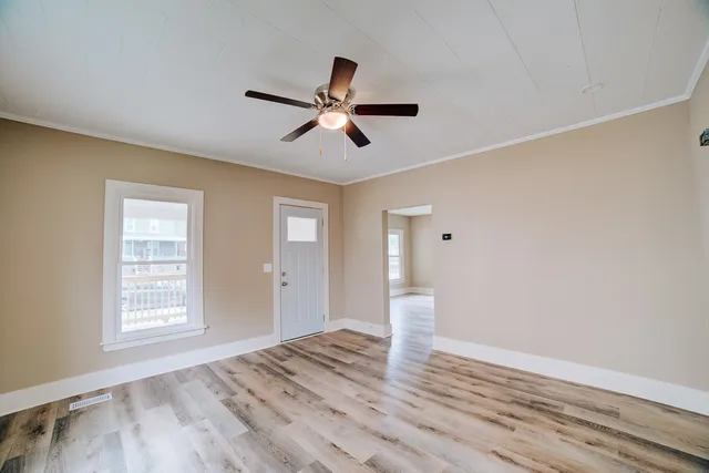 a view of empty room with wooden floor and fan