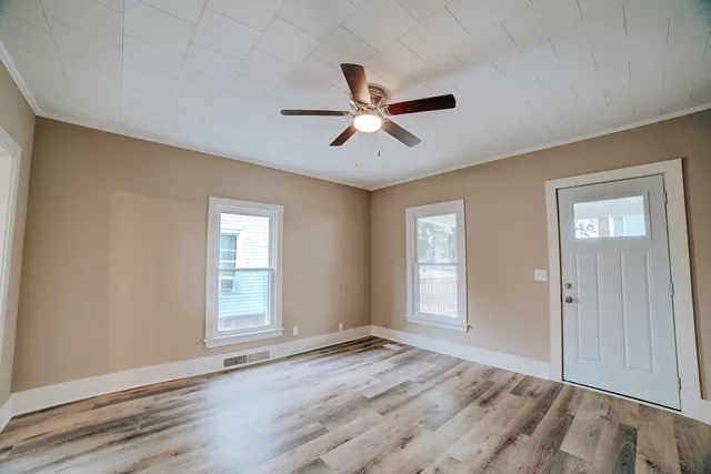 a view of empty room with wooden floor and fan