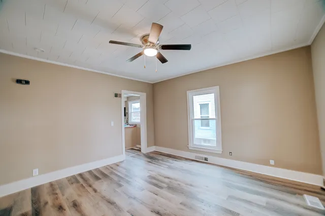 a view of empty room with wooden floor and fan