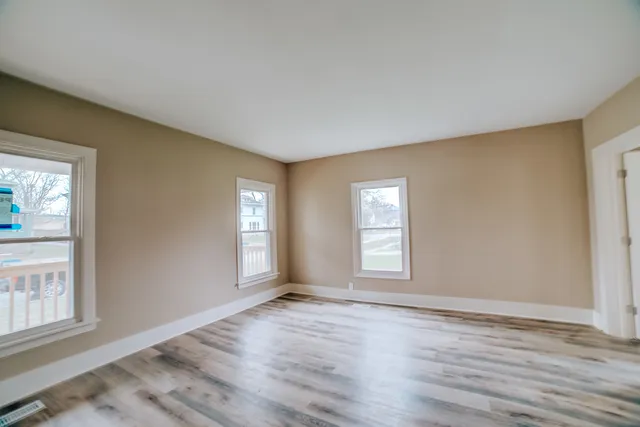 an empty room with wooden floor and windows