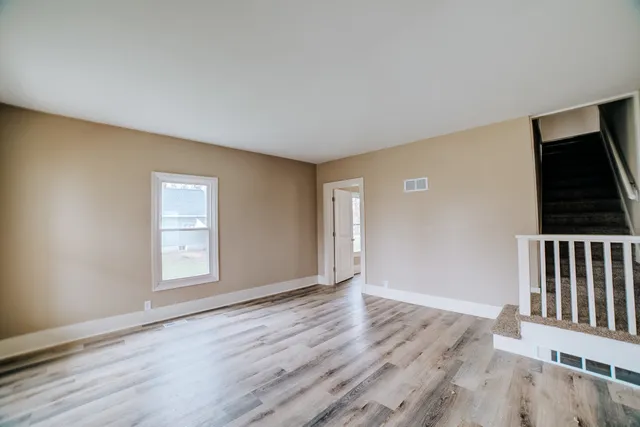 an empty room with wooden floor cabinet and windows