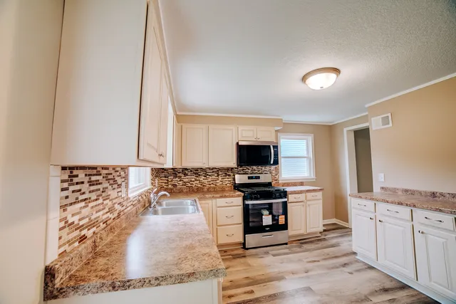 a kitchen with granite countertop a sink and a stove top oven