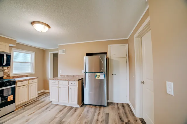 a kitchen with a refrigerator a stove top oven a sink and dishwasher with wooden floor