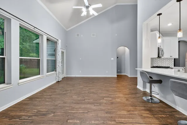 a view of an empty room with a window and wooden floor
