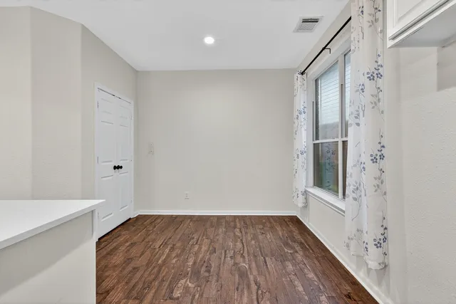 a view of a hallway with wooden floor and a bathroom