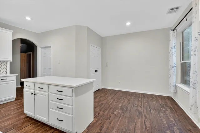 a kitchen with a wooden floor and white cabinets