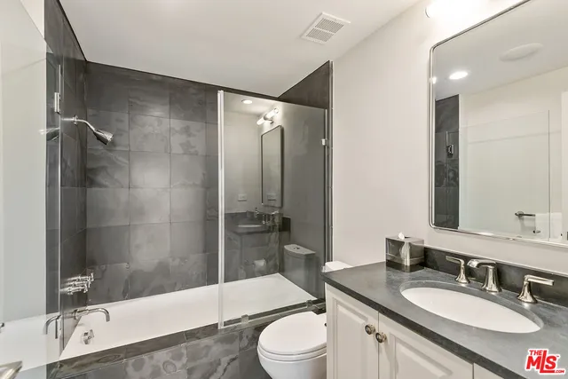 a bathroom with a granite countertop sink toilet mirror and bathtub