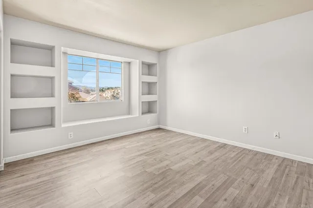 an empty room with wooden floor and a window