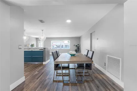 a kitchen with stainless steel appliances a dining table chairs and wooden floor