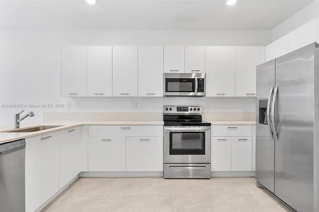 a kitchen with white cabinets and stainless steel appliances