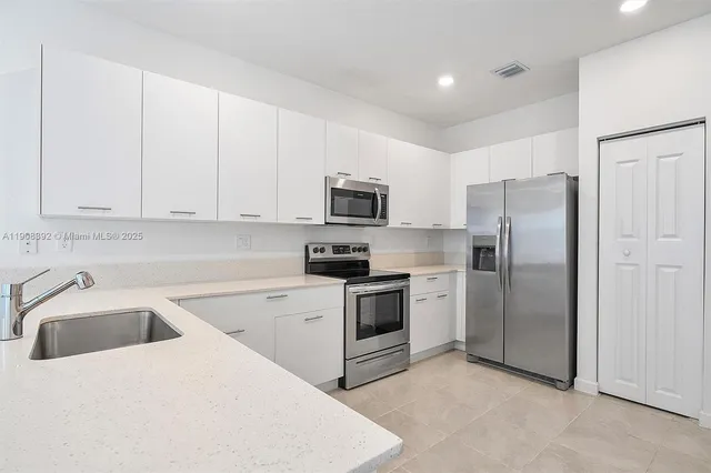a kitchen with white cabinets and stainless steel appliances