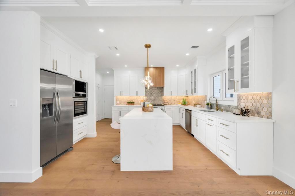 126 Rim Lane Hicksville, NY 11801 - Photo 11 of 28 Kitchen with a center island, hanging light fixtures, white cabinets, appliances with stainless steel finishes, and light stone countertops