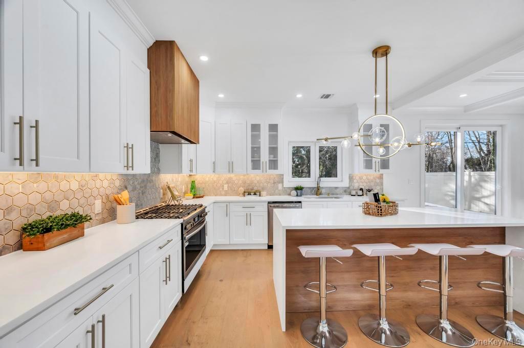 126 Rim Lane Hicksville, NY 11801 - Photo 12 of 28 Kitchen featuring white cabinetry, a breakfast bar area, light stone countertops, decorative light fixtures, and glass insert cabinets