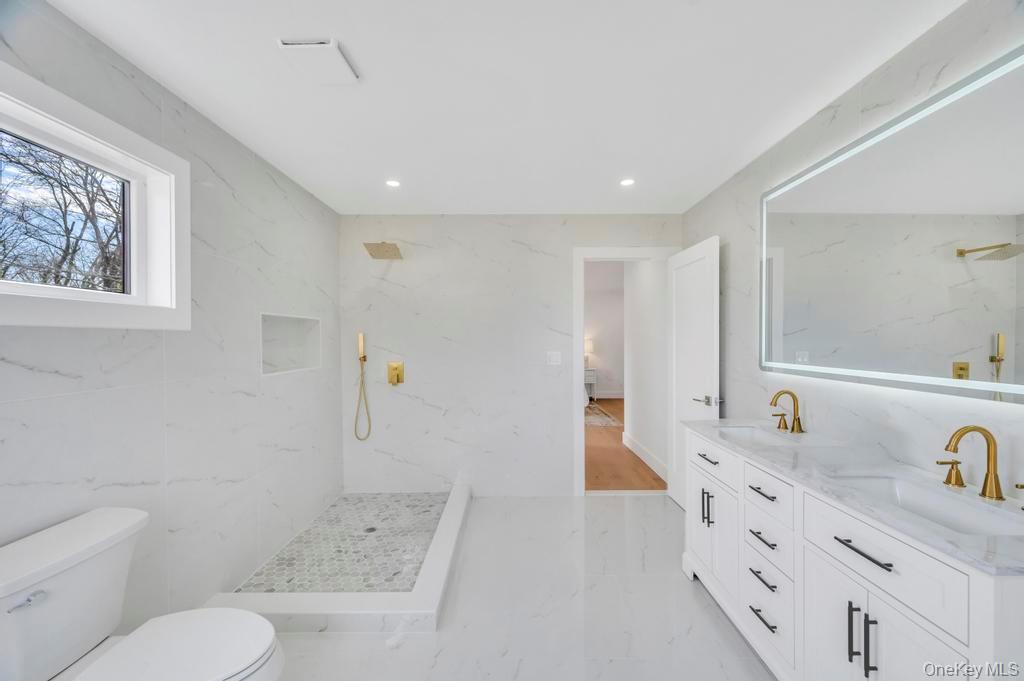 126 Rim Lane Hicksville, NY 11801 - Photo 14 of 28 Bathroom featuring double vanity, stone wall, a marble finish shower, light marble finish flooring, and recessed lighting