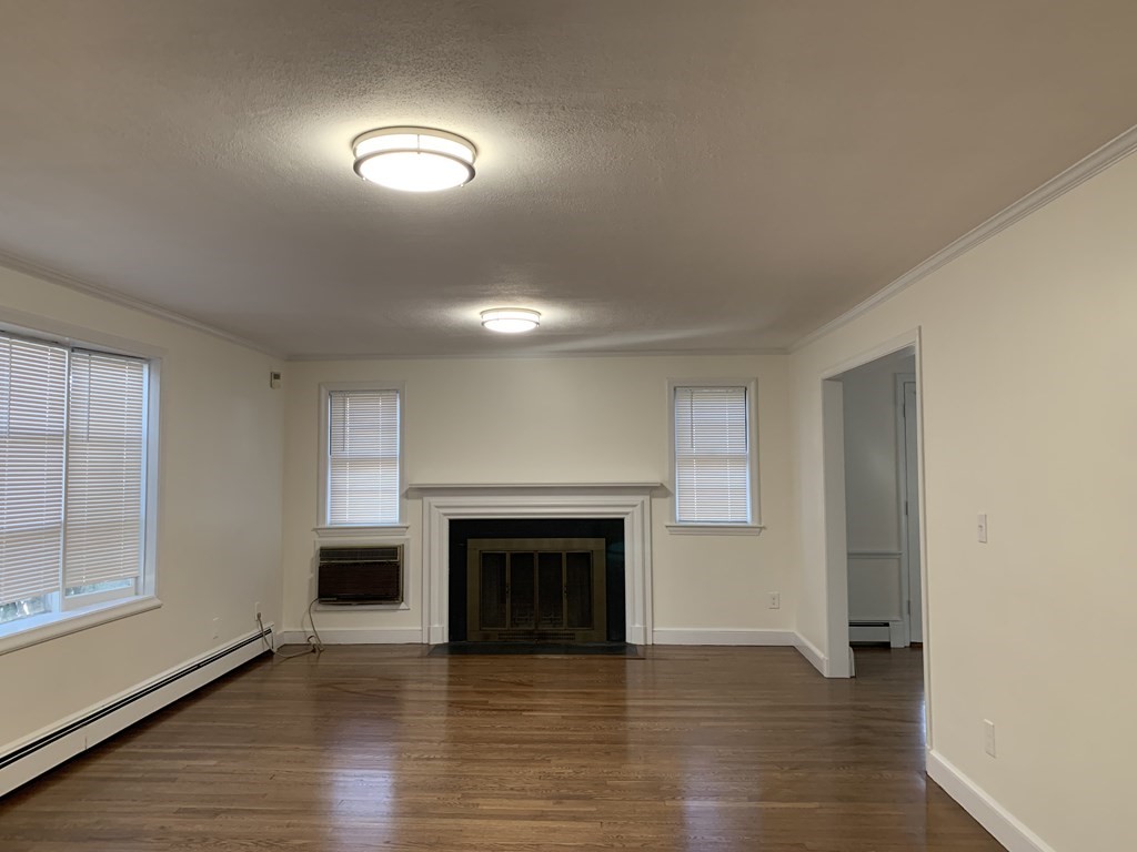 an empty room with wooden floor fireplace and windows
