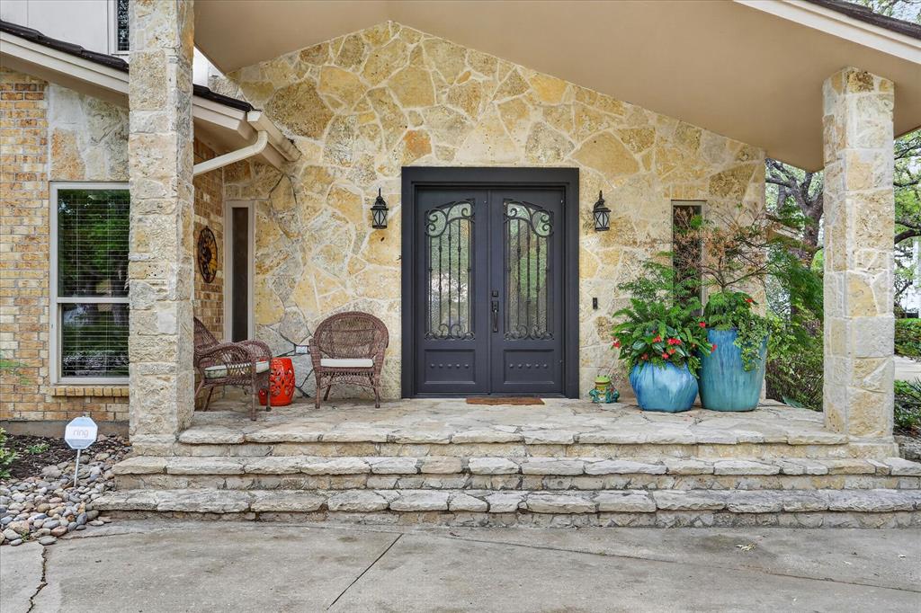 8877 Random Road Fort Worth, TX 76179 - Photo 2 of 40 Stacked stone facade entry featuring a double door with wrought iron detailing, covered porch, multiple stone columns, and stone steps