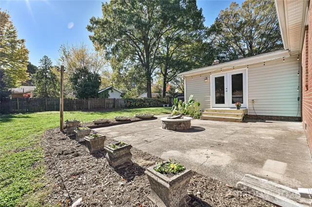 a view of a backyard with table and chairs potted plants and large tree
