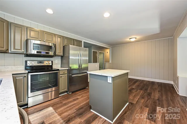 a kitchen with a sink wooden floor and stainless steel appliances