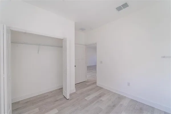 a view of an empty room with wooden floor and closet