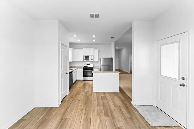 a kitchen with stainless steel appliances a refrigerator a stove top oven and wooden floor