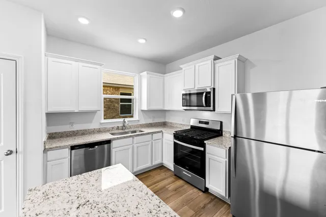 a kitchen with stainless steel appliances granite countertop a refrigerator sink stove microwave and cabinets