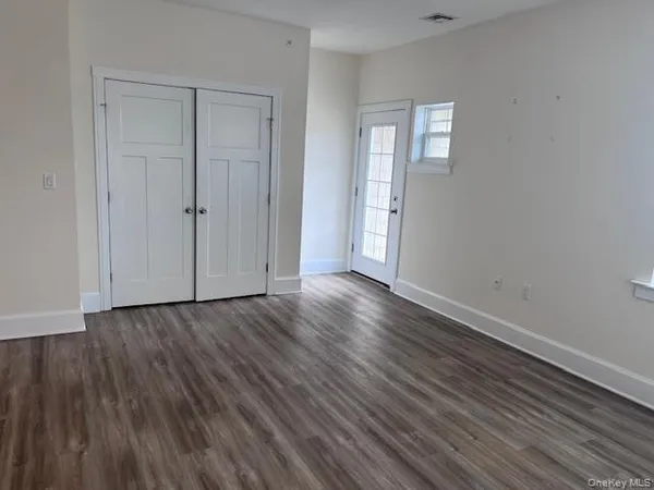 a view of an empty room with wooden floor and closet