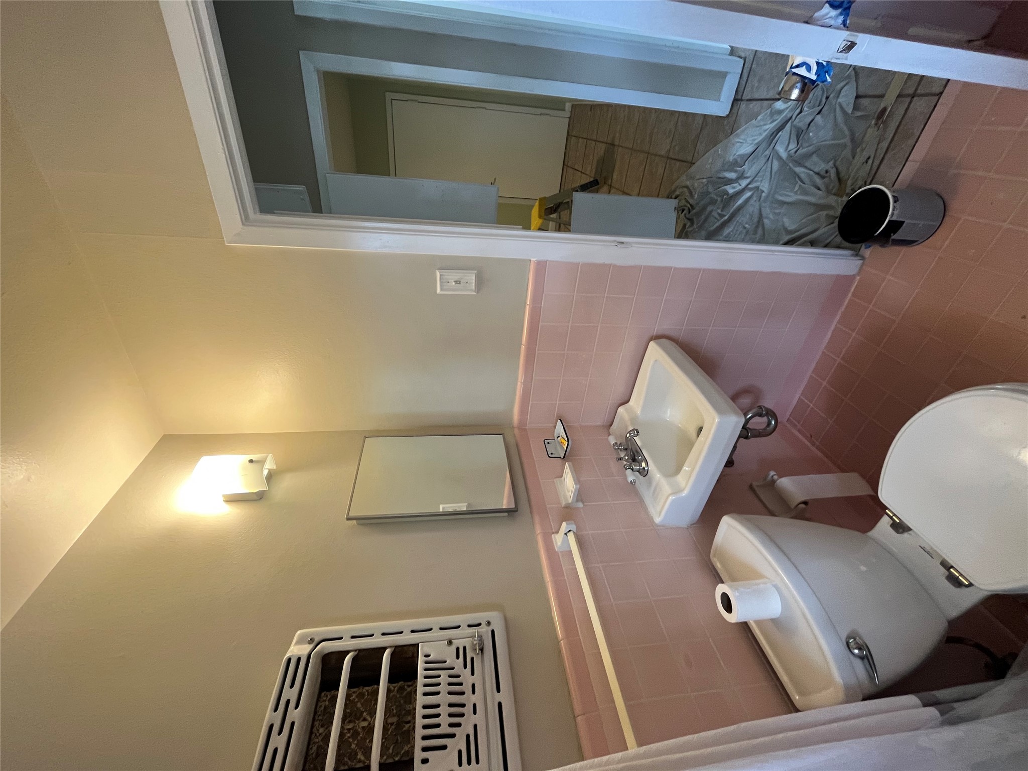 1607 Lightsey Road, Unit A Austin, TX 78704 - Photo 10 of 17 Bathroom featuring pink tile walls and flooring, a wall-mounted sink, and a white toilet