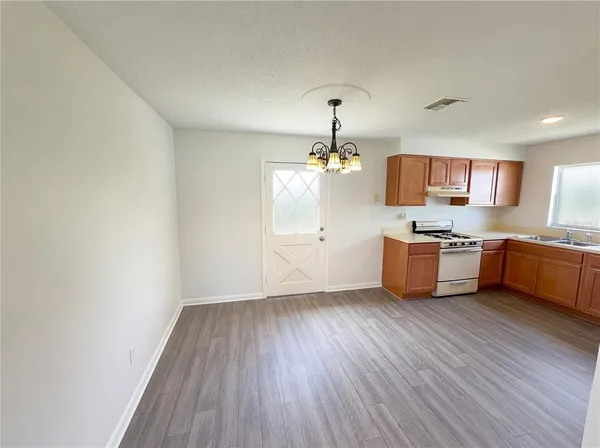 a kitchen with stainless steel appliances a stove a sink a refrigerator white cabinets and wooden floor