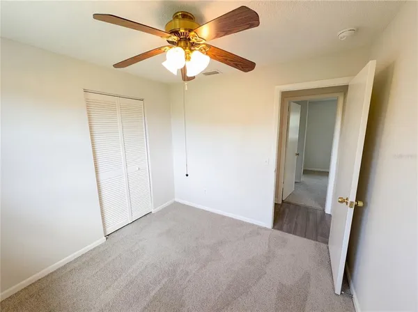 an empty room with windows and fan