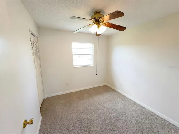 an empty room with a chandelier fan and closet