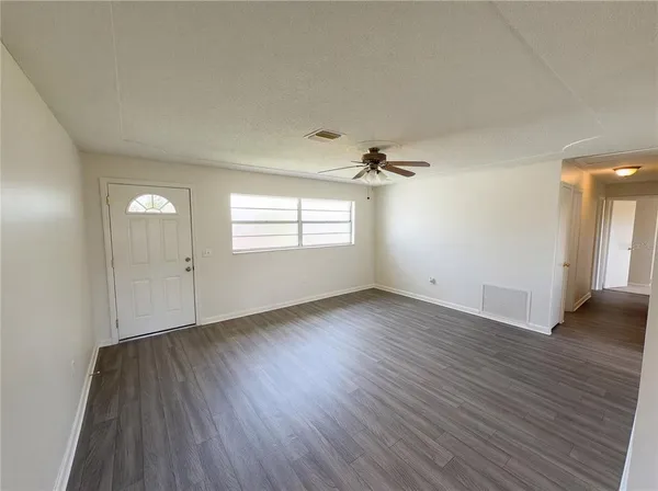 an empty room with wooden floor and windows
