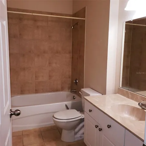 a bathroom with a granite countertop bathtub shower sink vanity and toilet