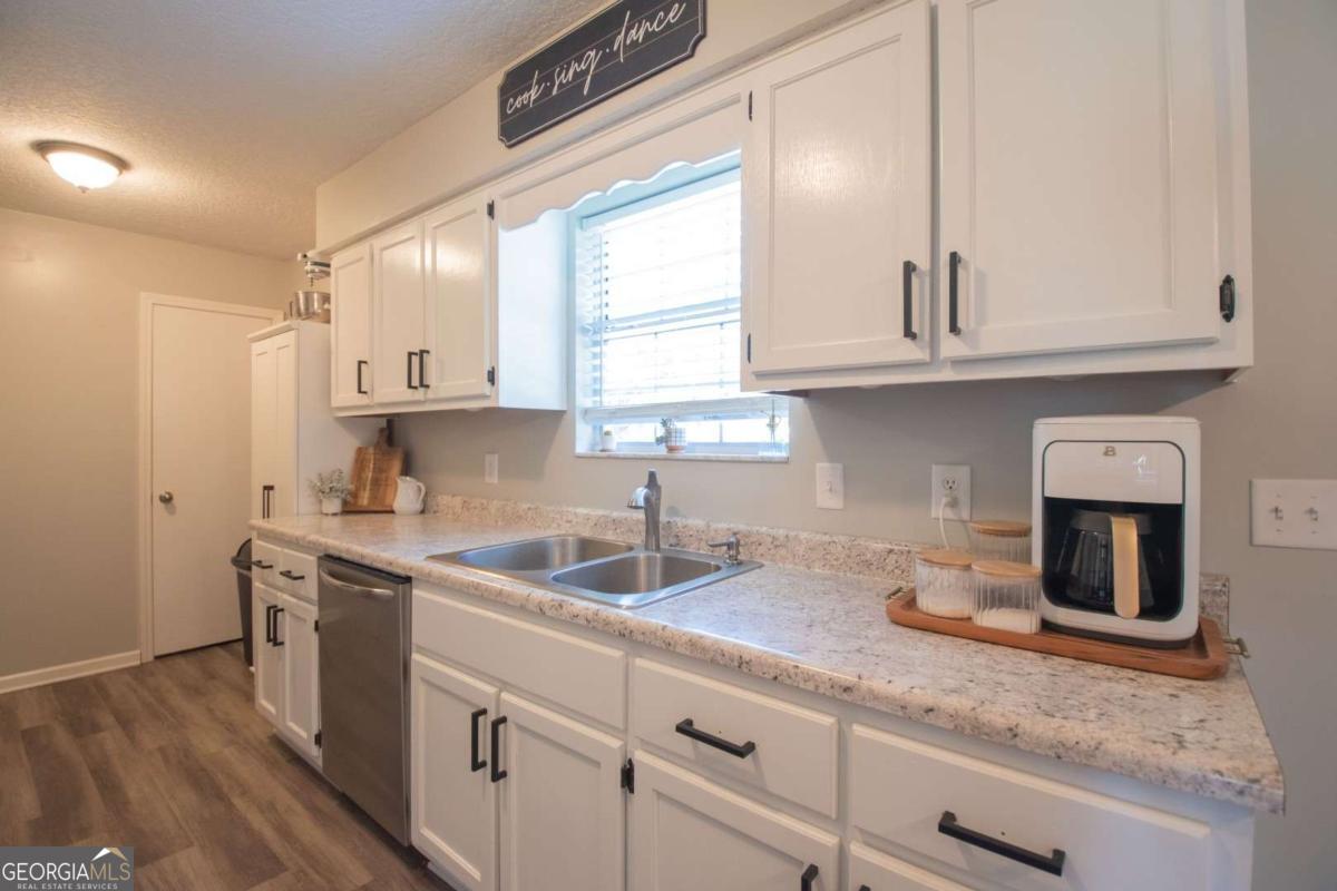 564 Dallas Circle Folkston, GA 31537 - Photo 12 of 21 a kitchen with granite countertop a sink stainless steel appliances white cabinets and a window