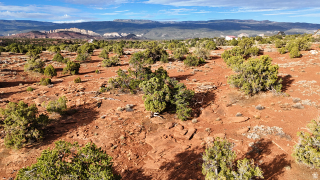 358 South Sky Drive Torrey, UT 84775 - Photo 57 of 82 Expansive desert landscape featuring red earth, scattered green shrubbery, and distant mountain ranges under a blue sky