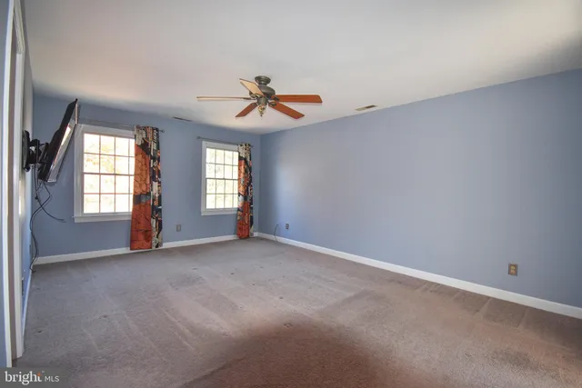 an empty room with windows and ceiling fan