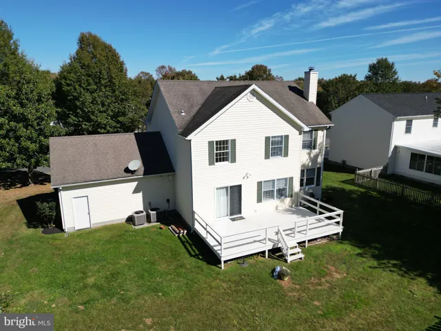 a white bench sitting in the grass near a house