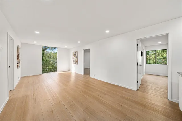 a view of a big room with wooden floor and windows