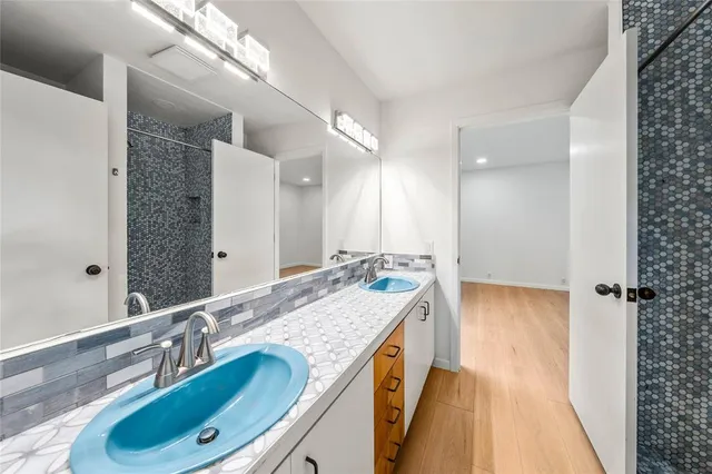 a bathroom with a granite countertop double vanity sink and mirror