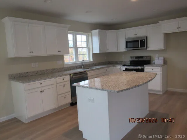 a kitchen with granite countertop a sink a counter top space and cabinets