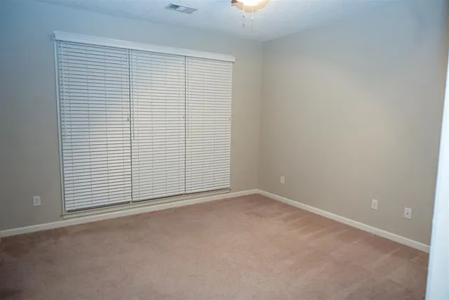 a view of an empty room with wooden floor and kitchen