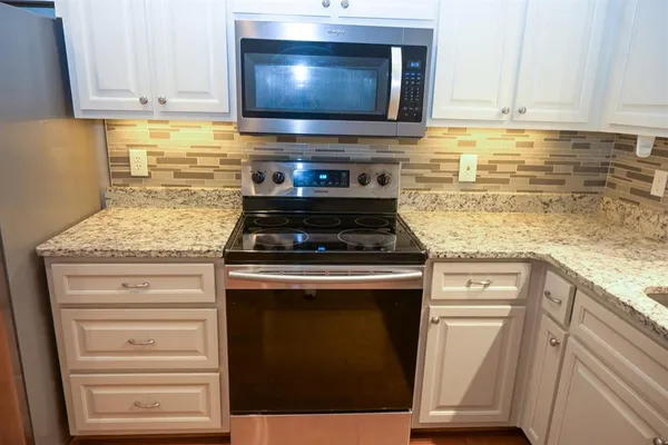 a kitchen with granite countertop a stove and a microwave