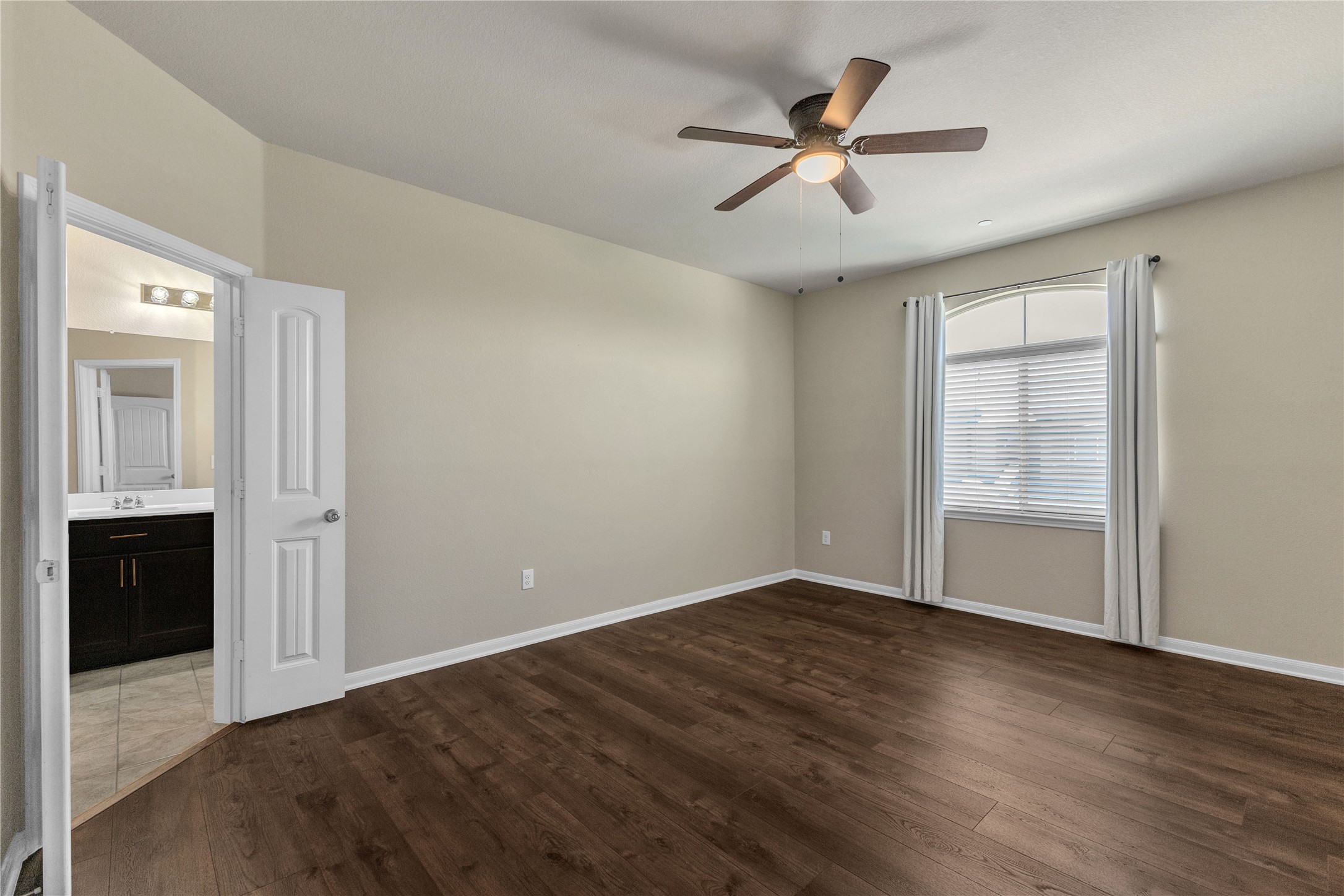 2880 Donnell Drive, Unit 2003 Round Rock, TX 78664 - Photo 19 of 31 Bedroom with wood-finish flooring, a ceiling fan with integrated lighting, and an arched window featuring blinds and drapes