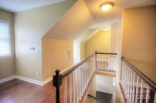 a view of a hallway with wooden floor and staircase