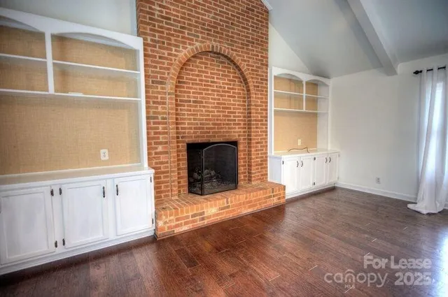 a living room with stainless steel appliances wooden floor and a fireplace