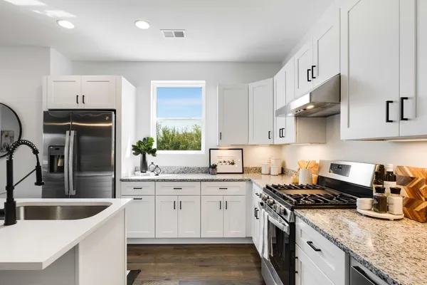 a kitchen with stainless steel appliances granite countertop a sink stove refrigerator and cabinets